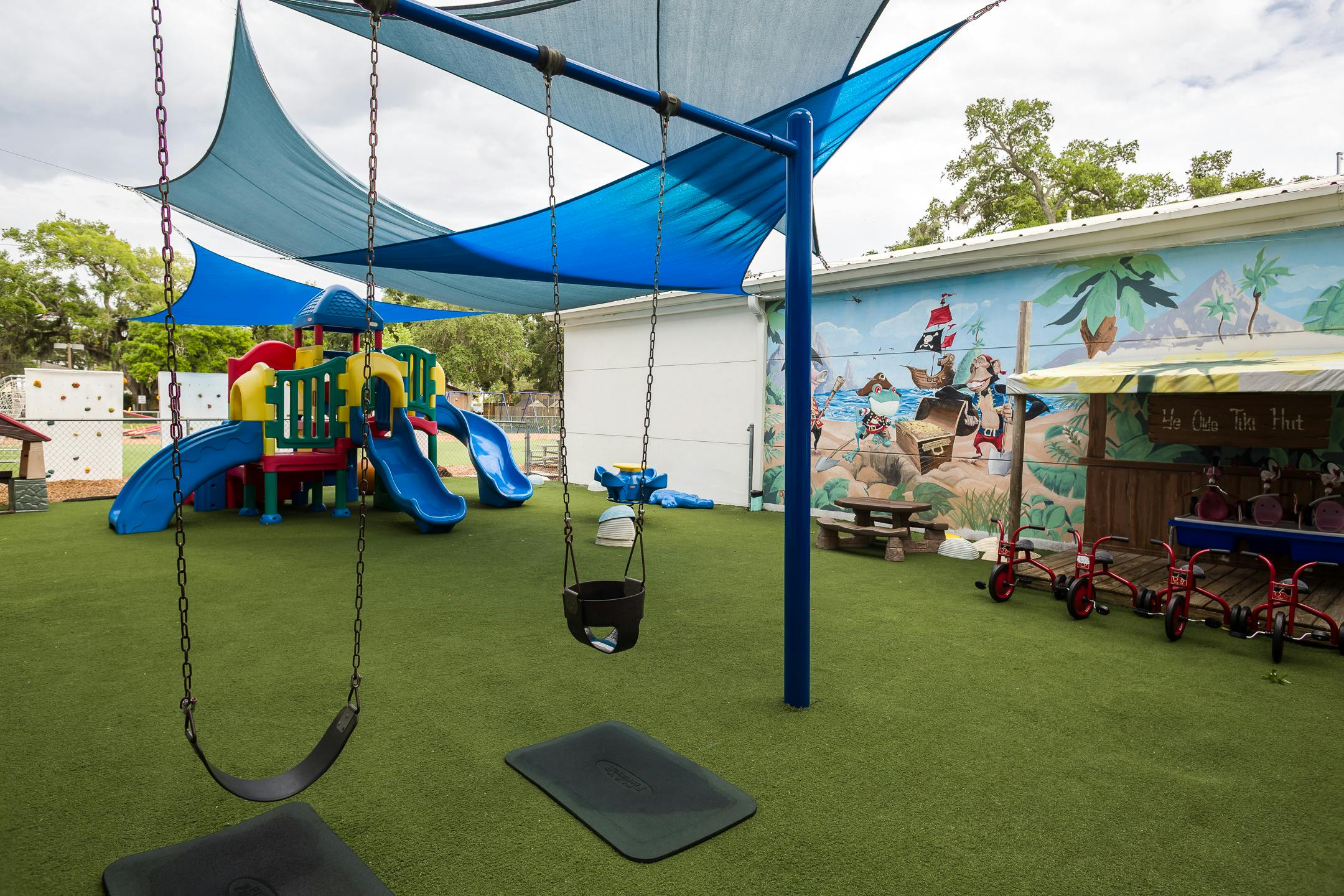 Outdoor playground with swings, slides, and shade sails