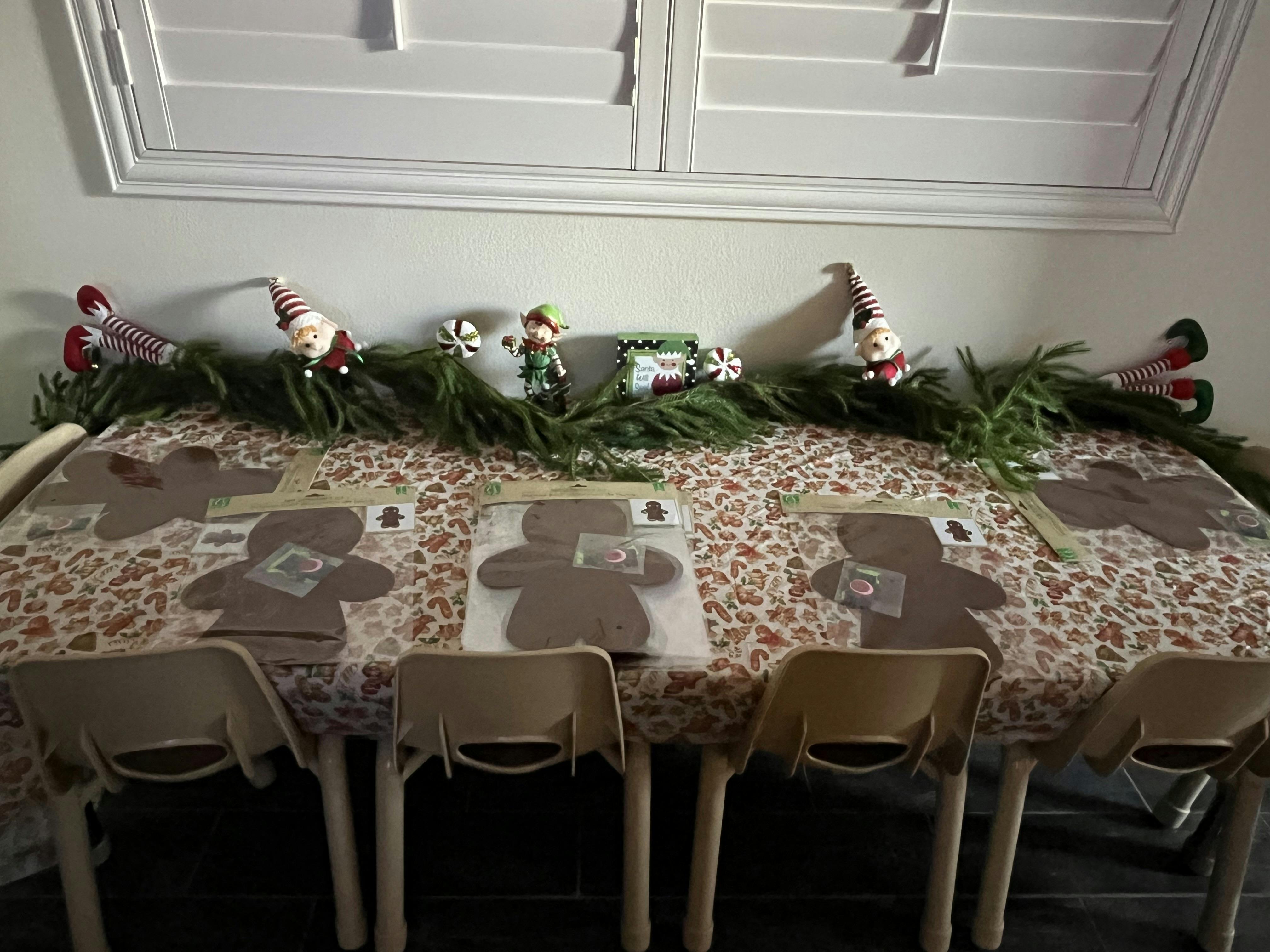 Gingerbread man craft kits arranged on a table with holiday elf decorations