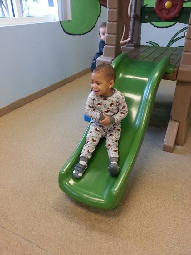 Child sitting on a green slide