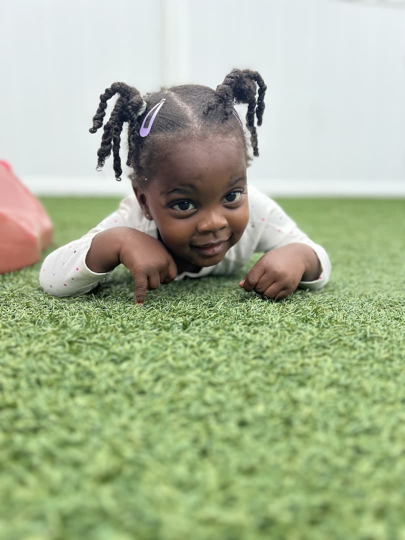 Child lying on green turf, looking forward
