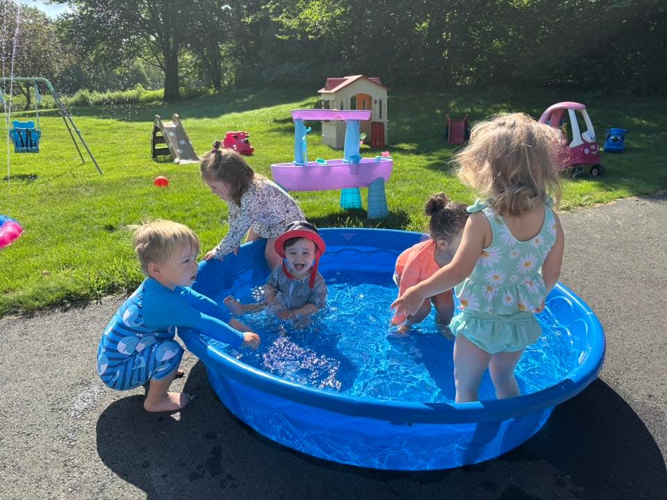 Children playing in a small blue wading pool