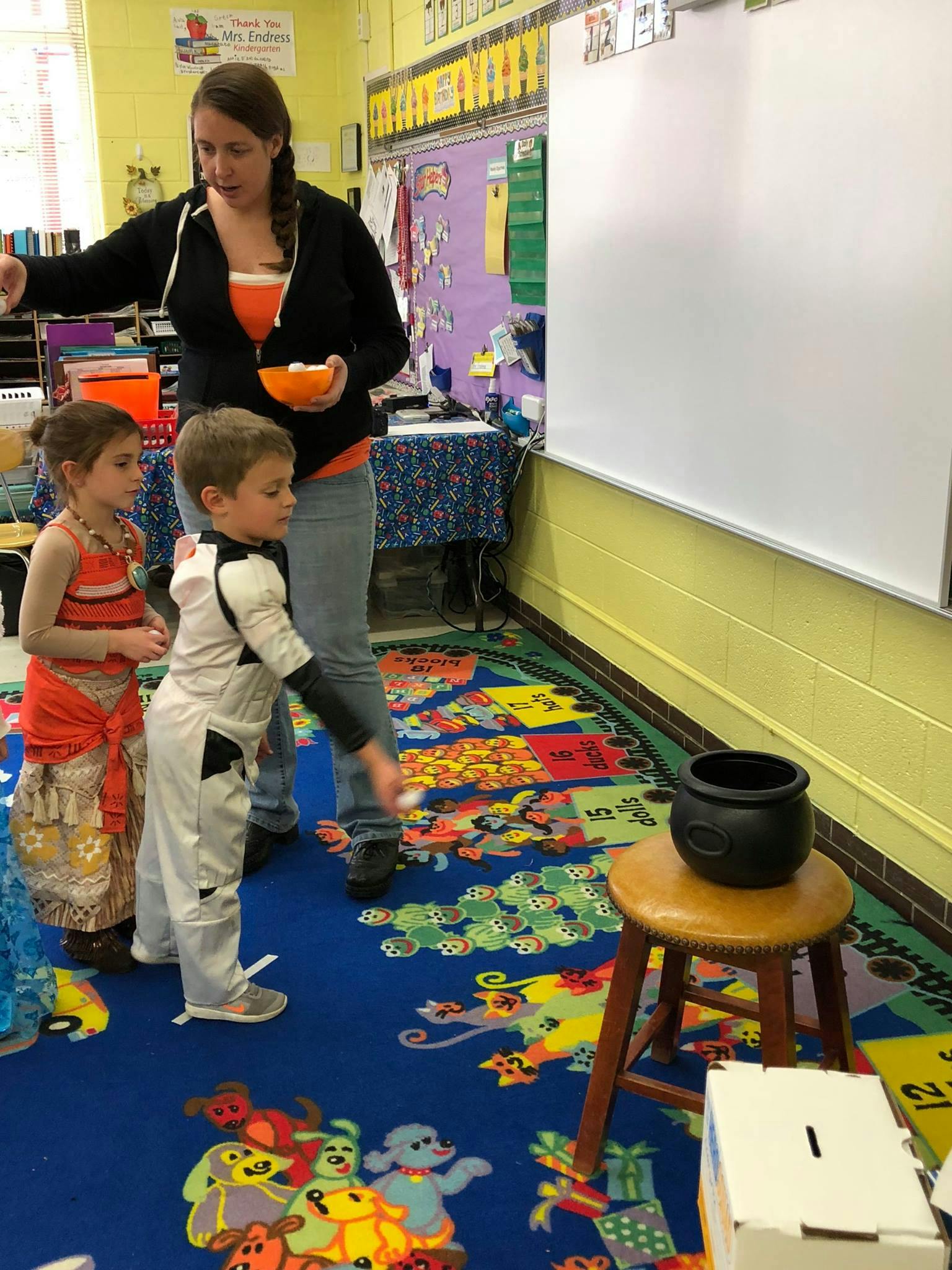 Adult and two children in a classroom, one child throwing a ball