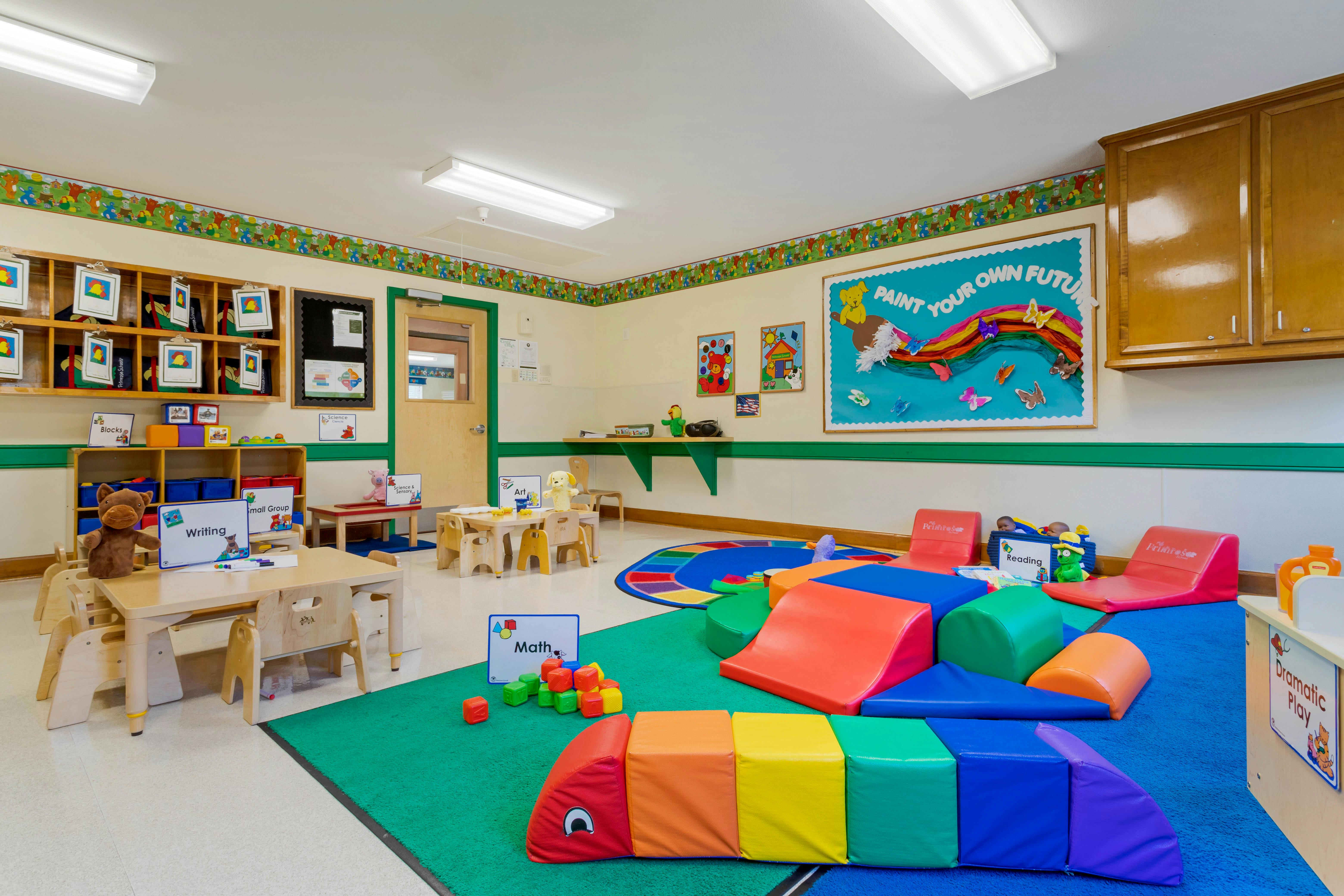 Colorful classroom with various activity stations, small tables, and play mats