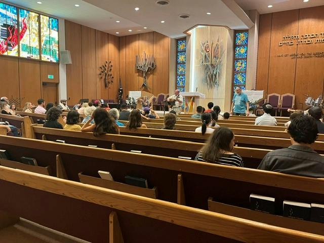 People seated in pews during a gathering in a synagogue