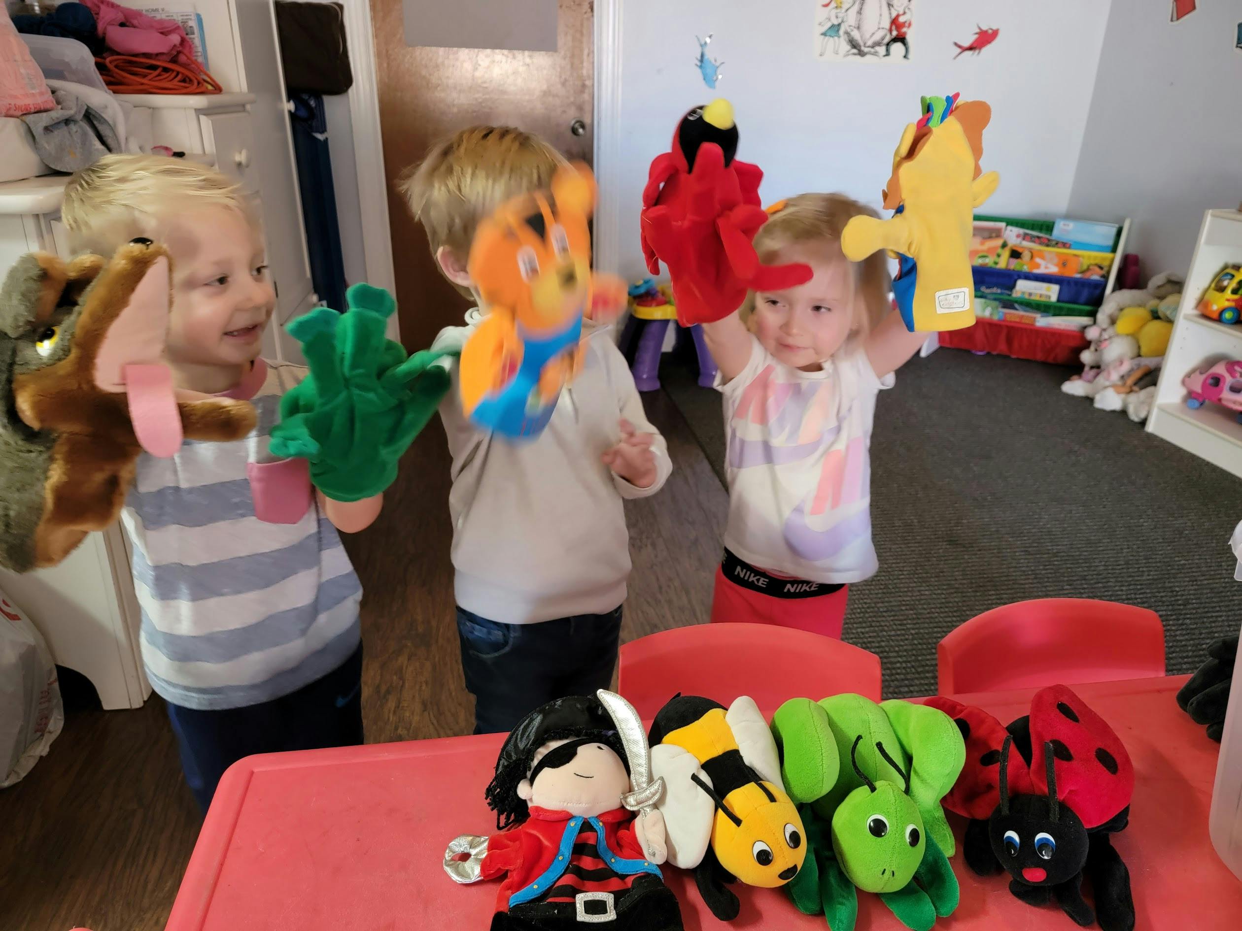 Three children playing with hand puppets