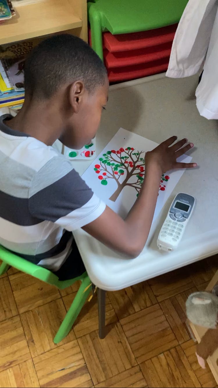 Child sitting at a table, looking at a drawing of a tree