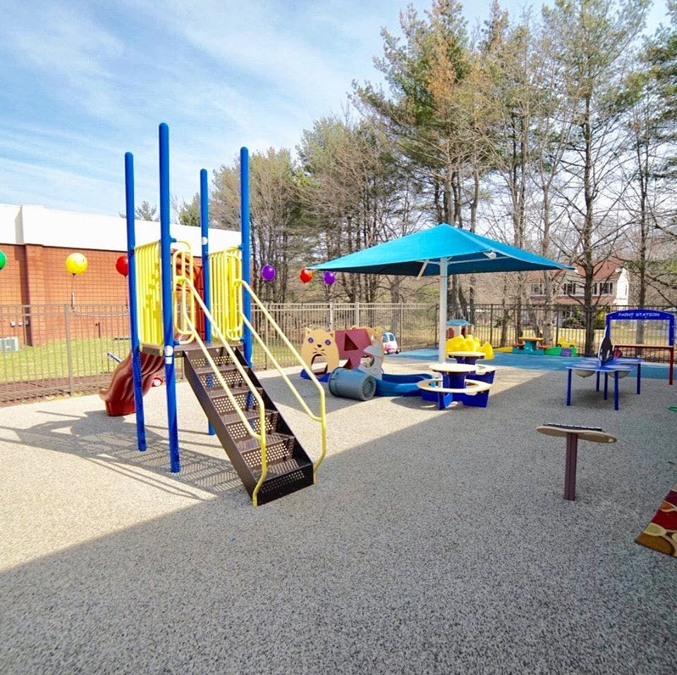 Empty outdoor playground with slides, stairs, and a blue umbrella