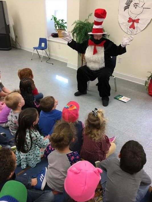 Person in Cat in the Hat costume sitting in front of children