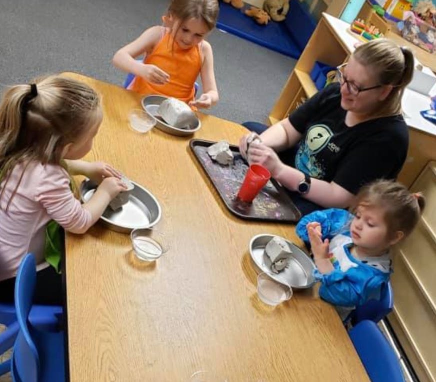 Adult and three children at a table with craft supplies