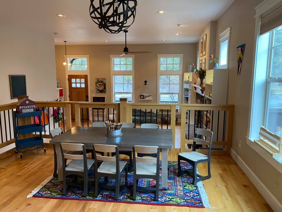 Dining table with chairs on a rug in a large room