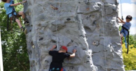 Three children climbing a rock wall