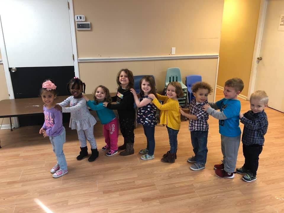Group of children standing in a line, holding onto each other