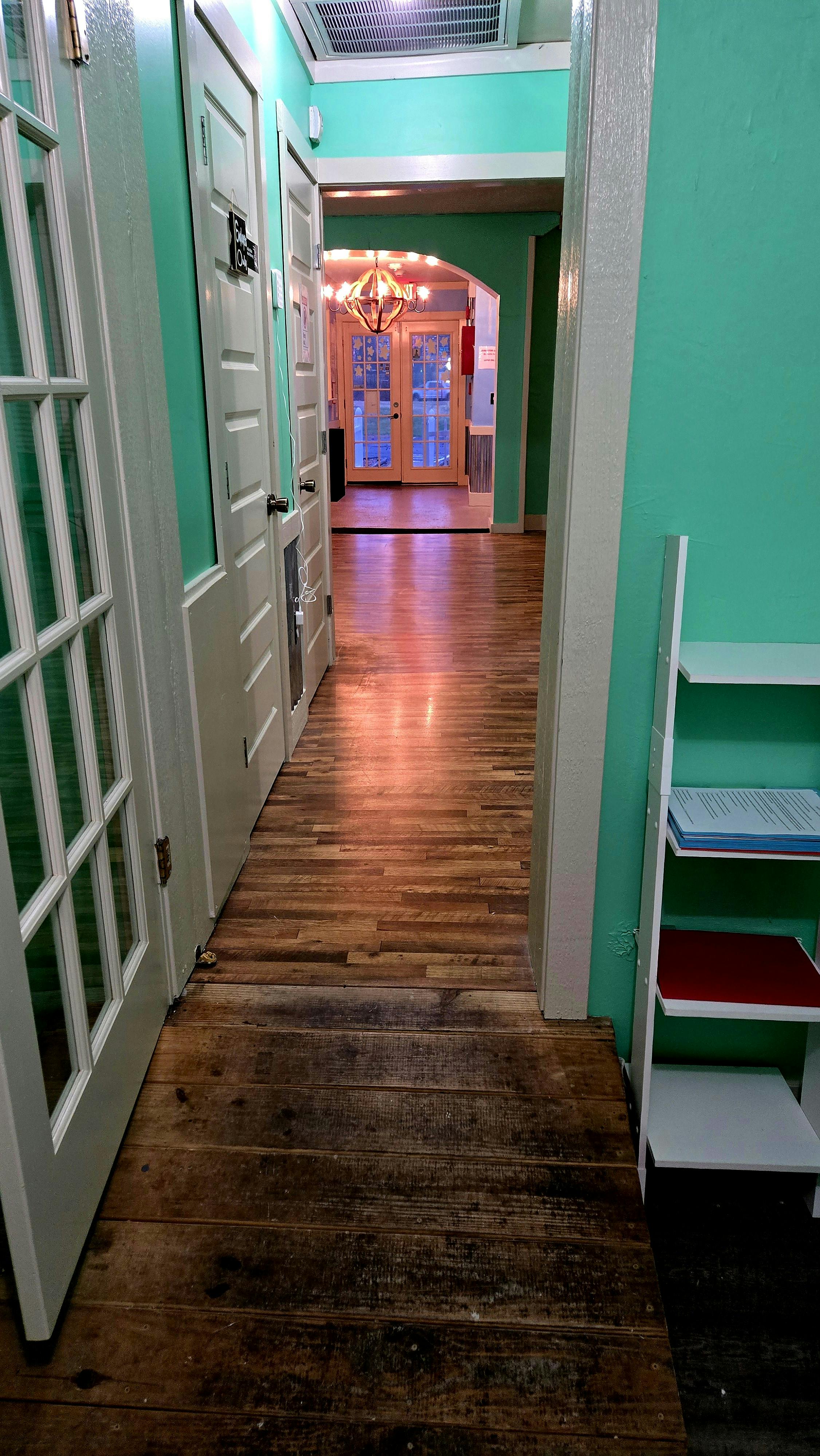 Hallway with wooden floor and teal walls leading to an arched doorway