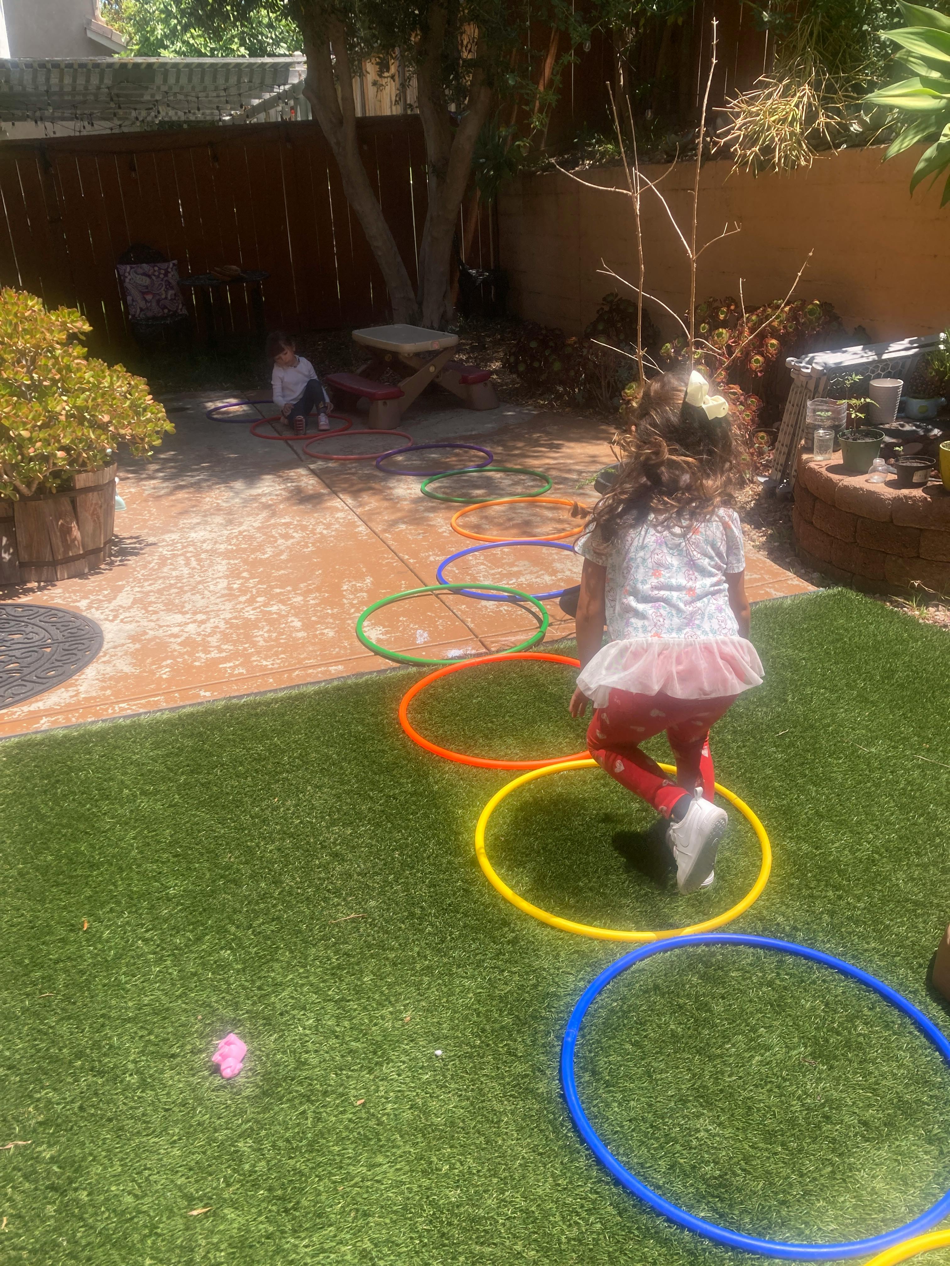 Child stepping through colorful hoops on grass and pavement
