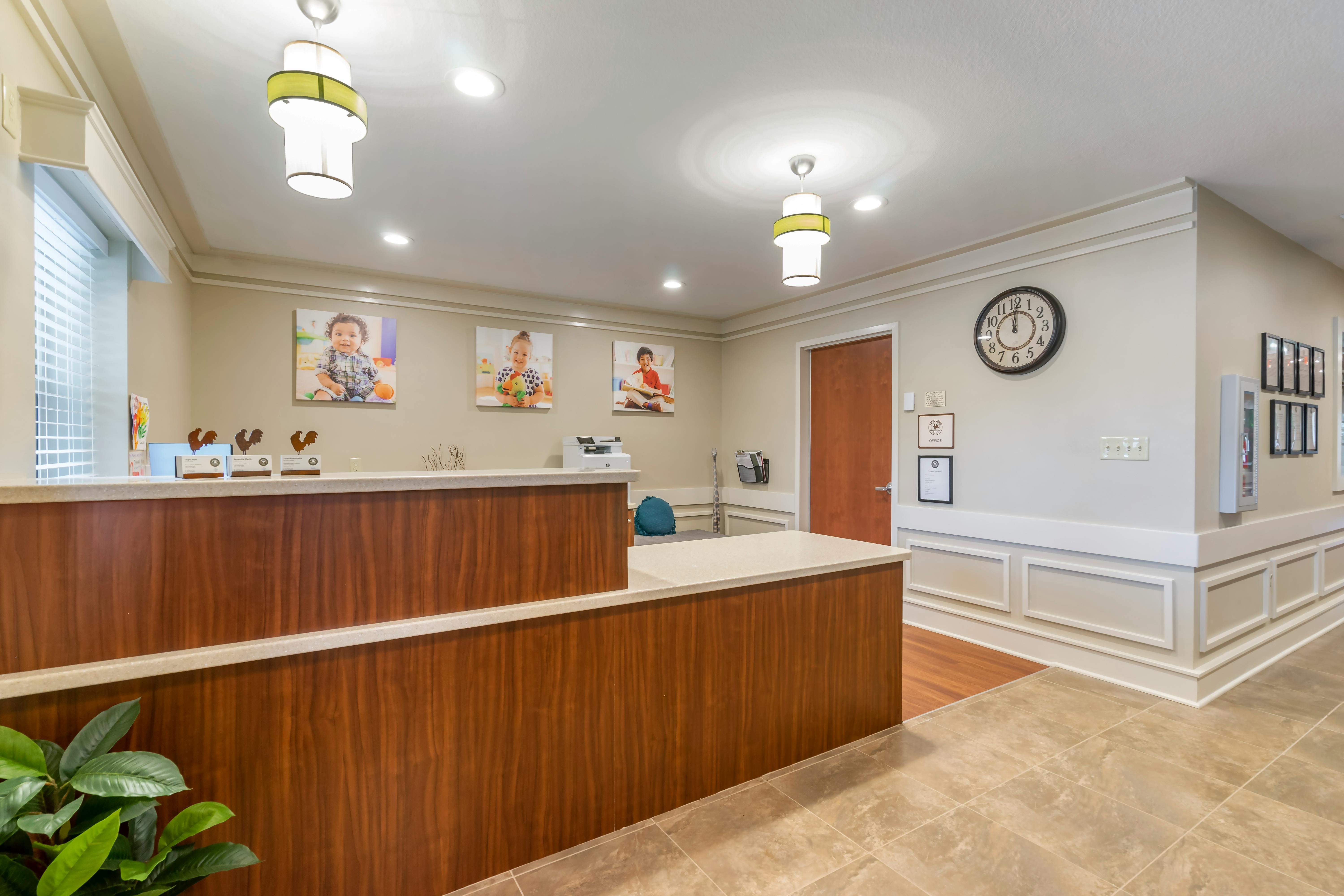 Reception desk with wood paneling and three pictures of children on the wall