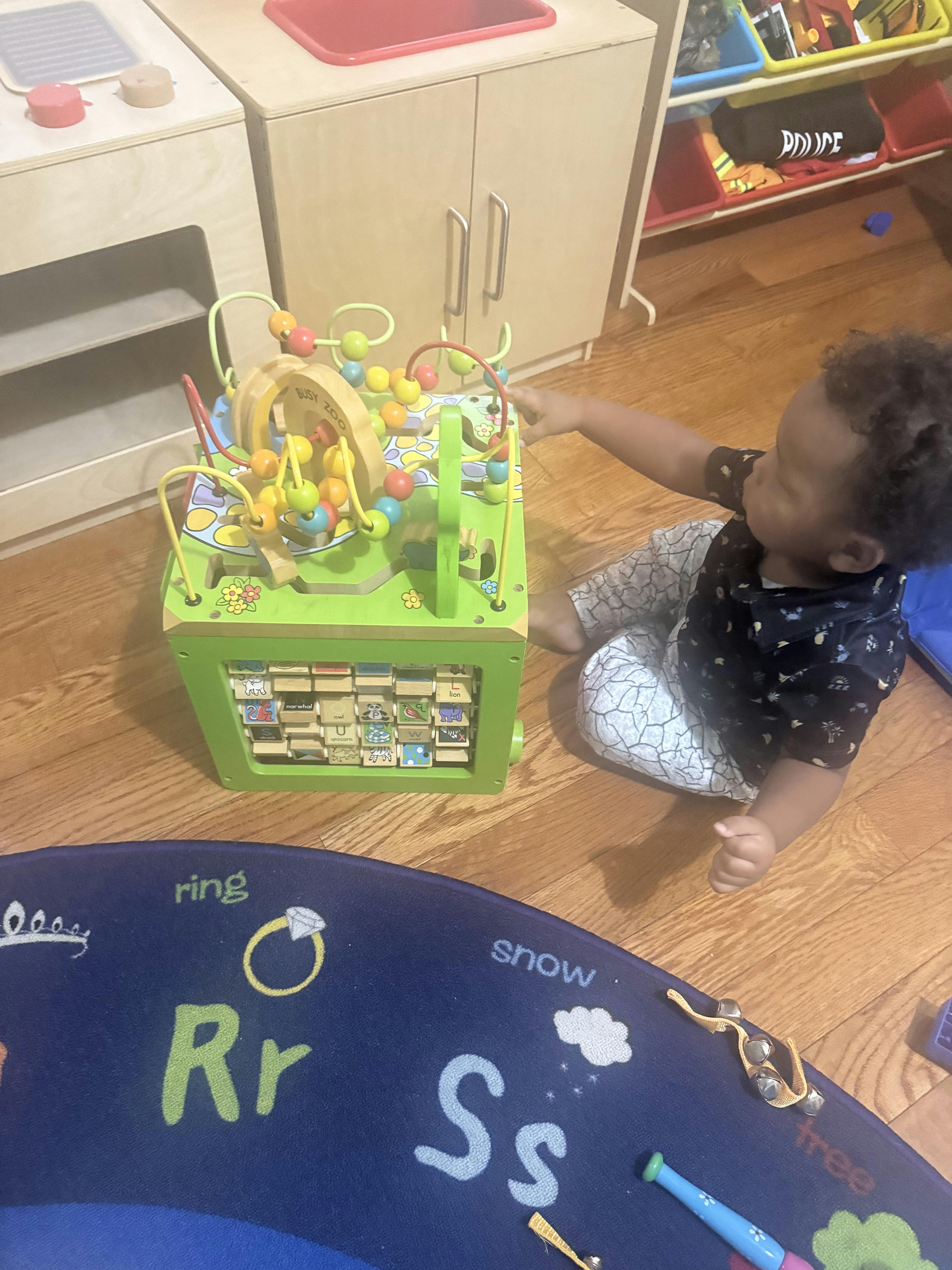 Child playing with a wooden activity cube on a play mat