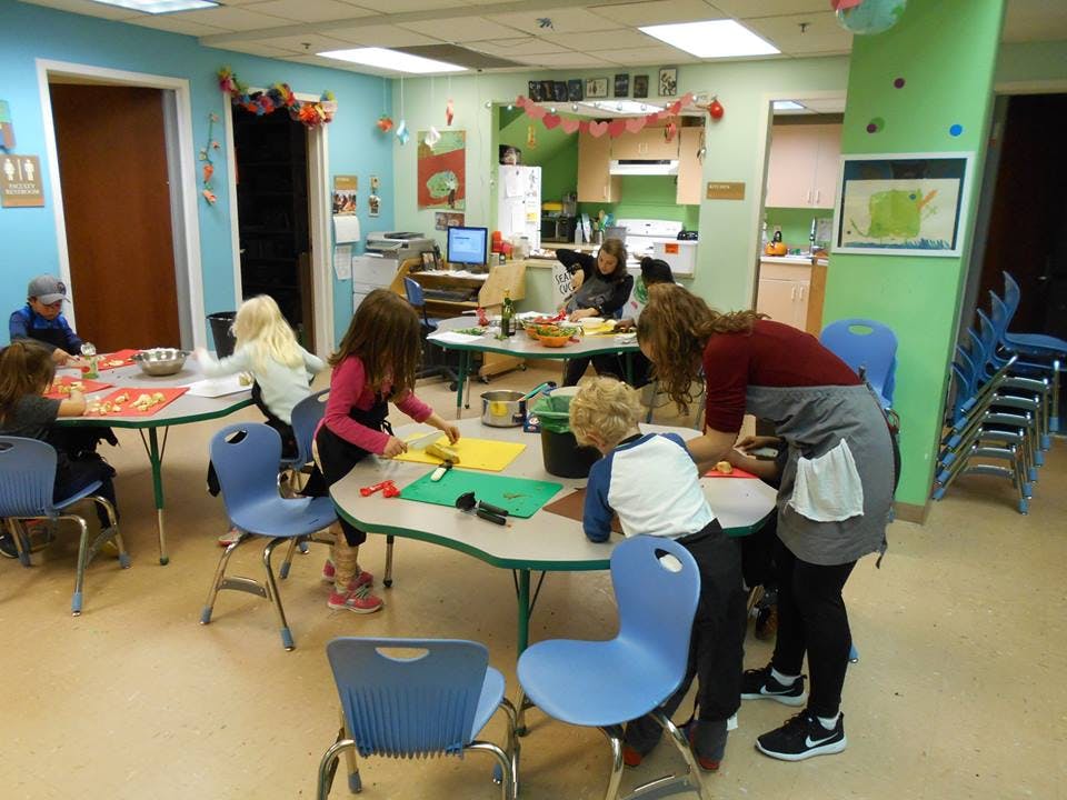 Adults and children working on crafts at tables in a classroom