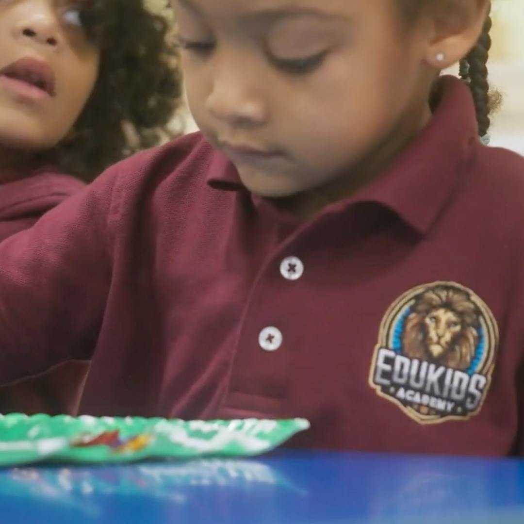 Child in a maroon polo shirt with an Edukids Academy logo