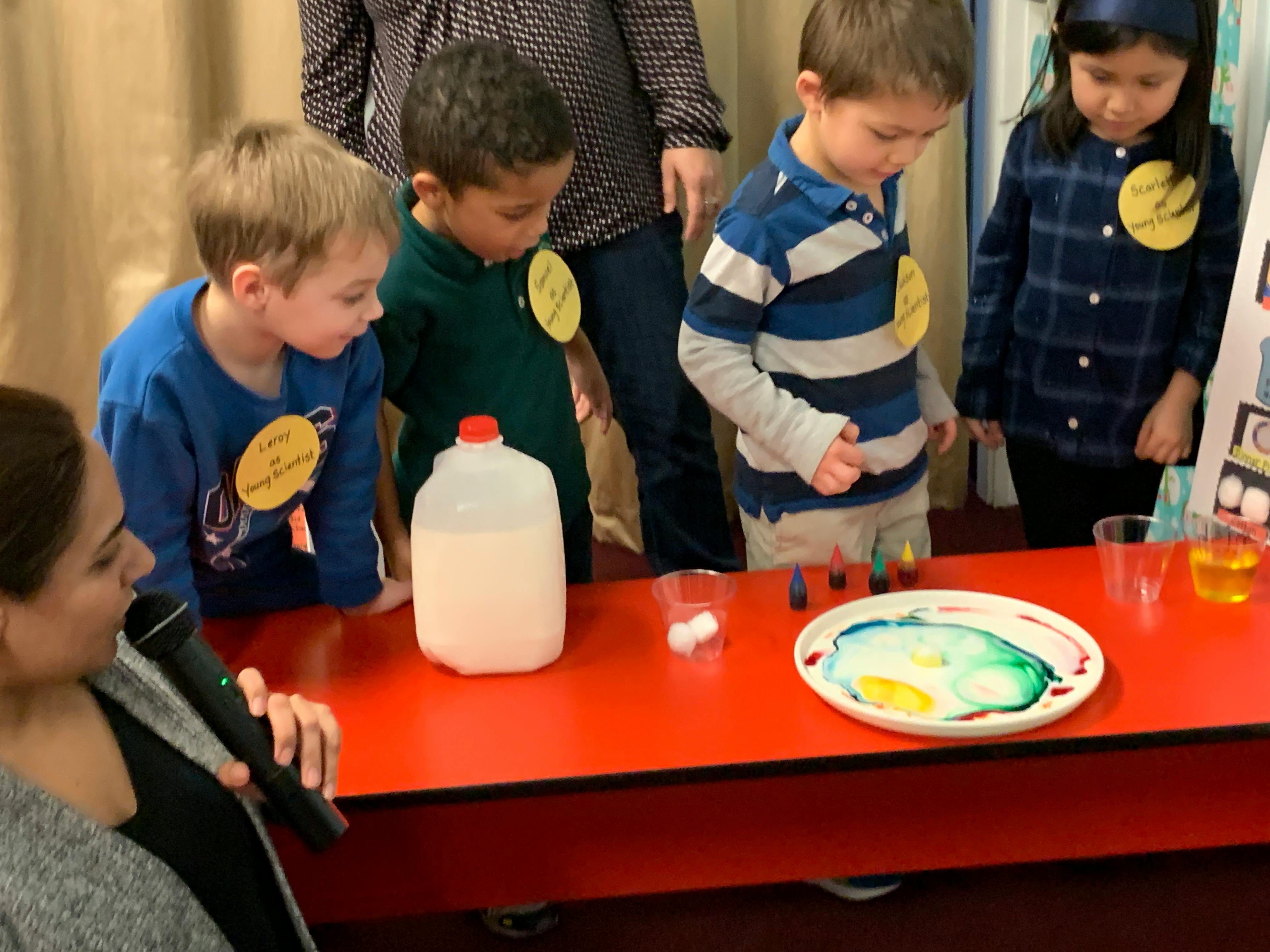 Children watching a science experiment with milk and food coloring