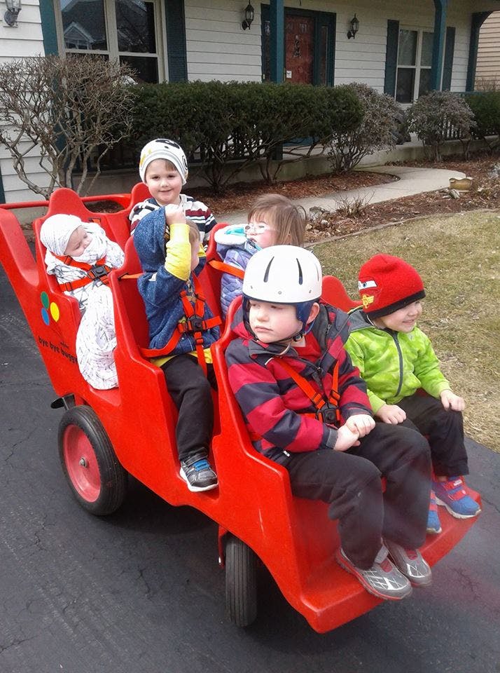 Multiple children riding in a red multi-seat wagon