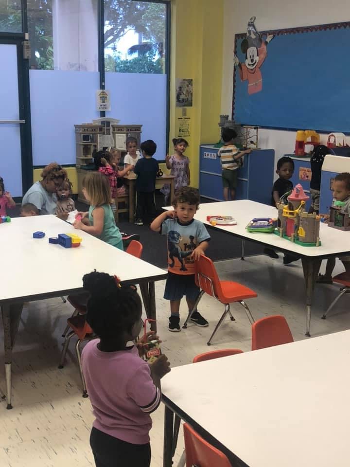 Children and adults in a classroom with tables and chairs