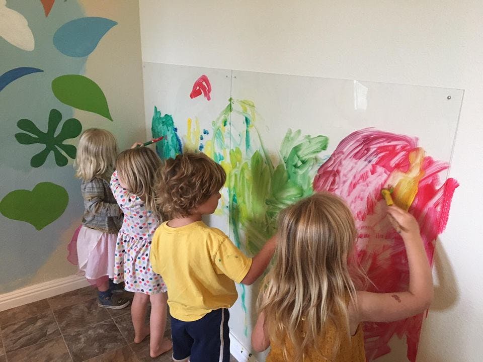 Children painting on a clear board in a classroom