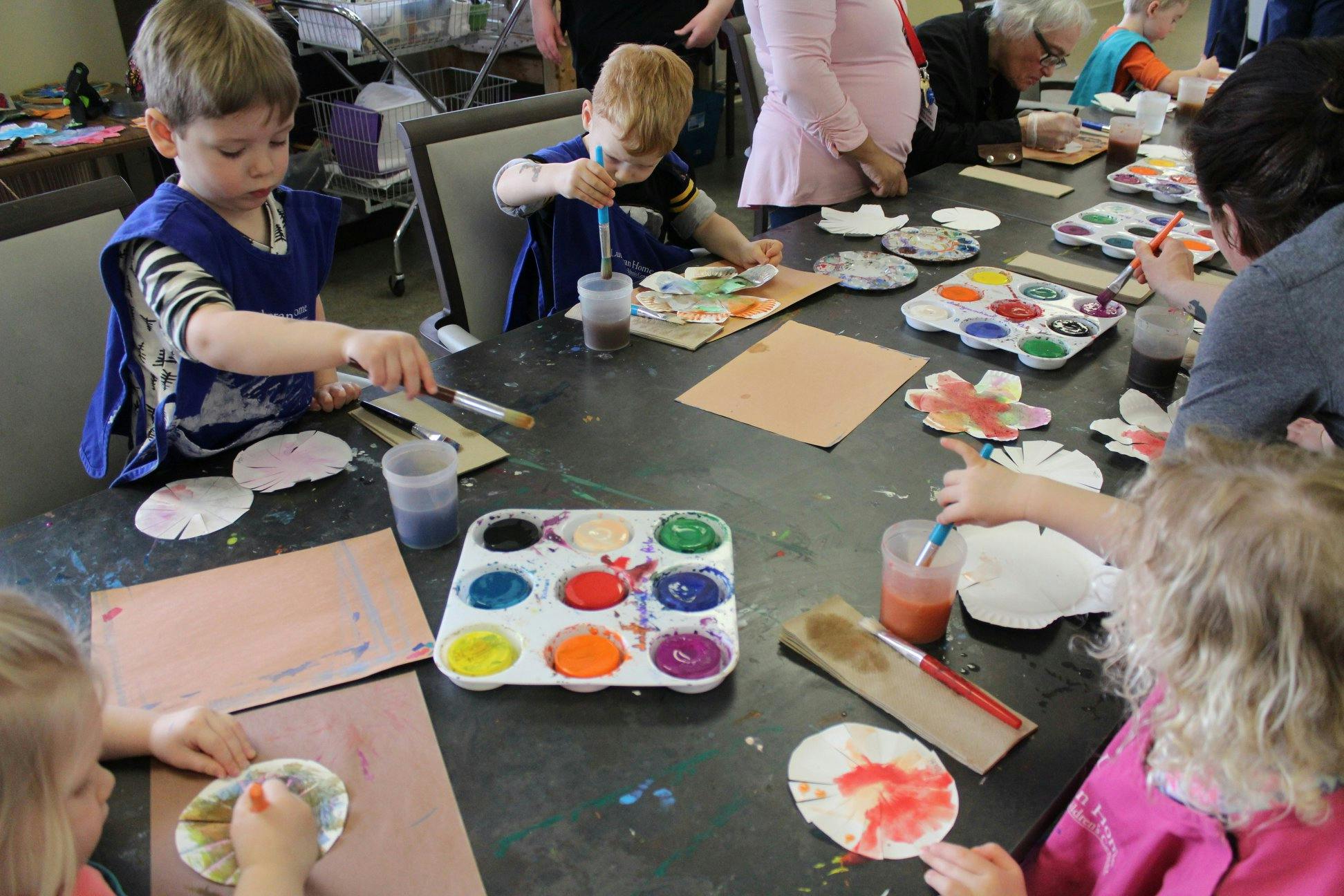 Children and adults painting at a table