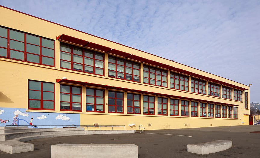 Exterior of a school building with multiple windows and a mural