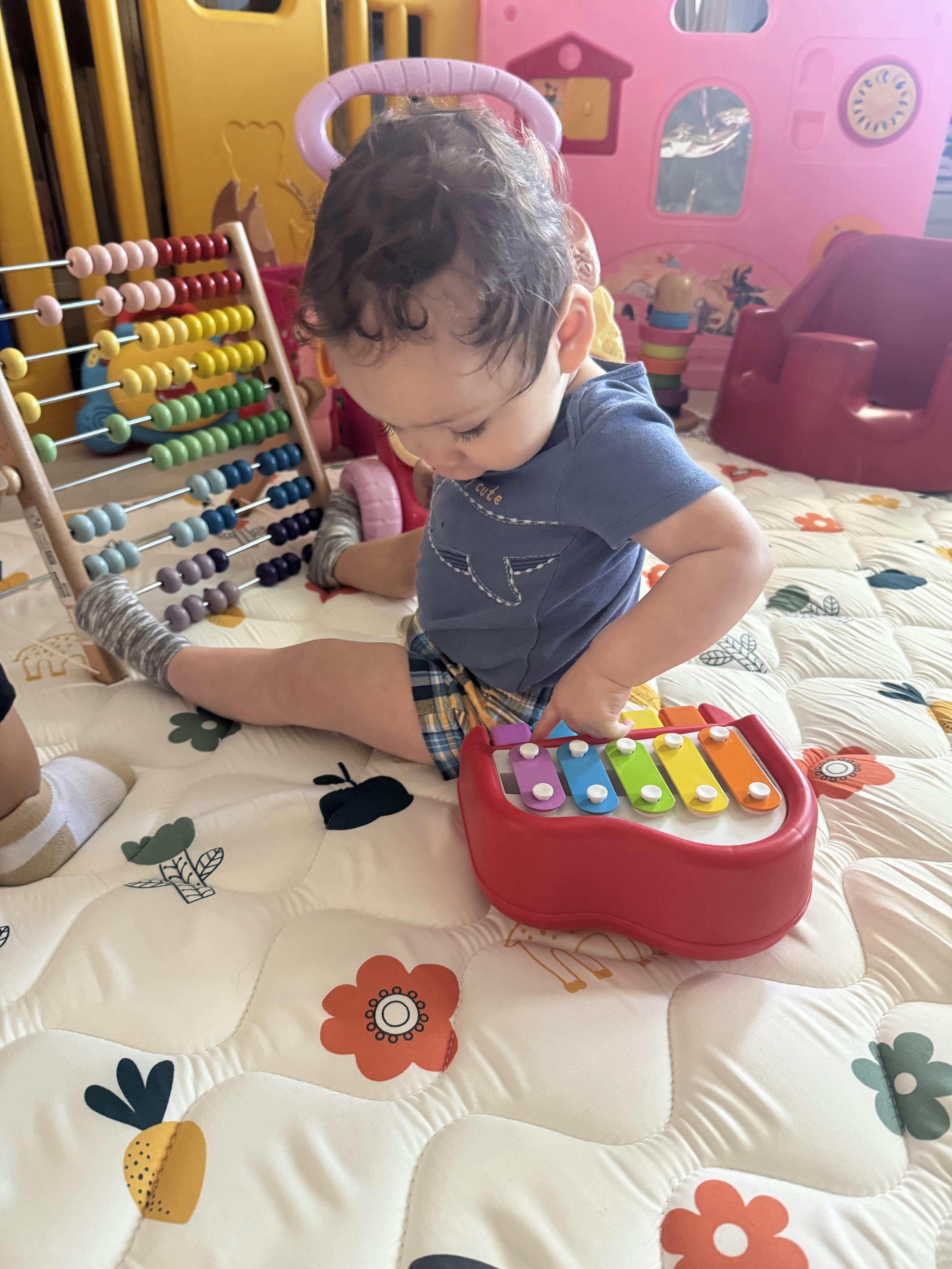 Child sitting on a play mat and playing with a toy xylophone