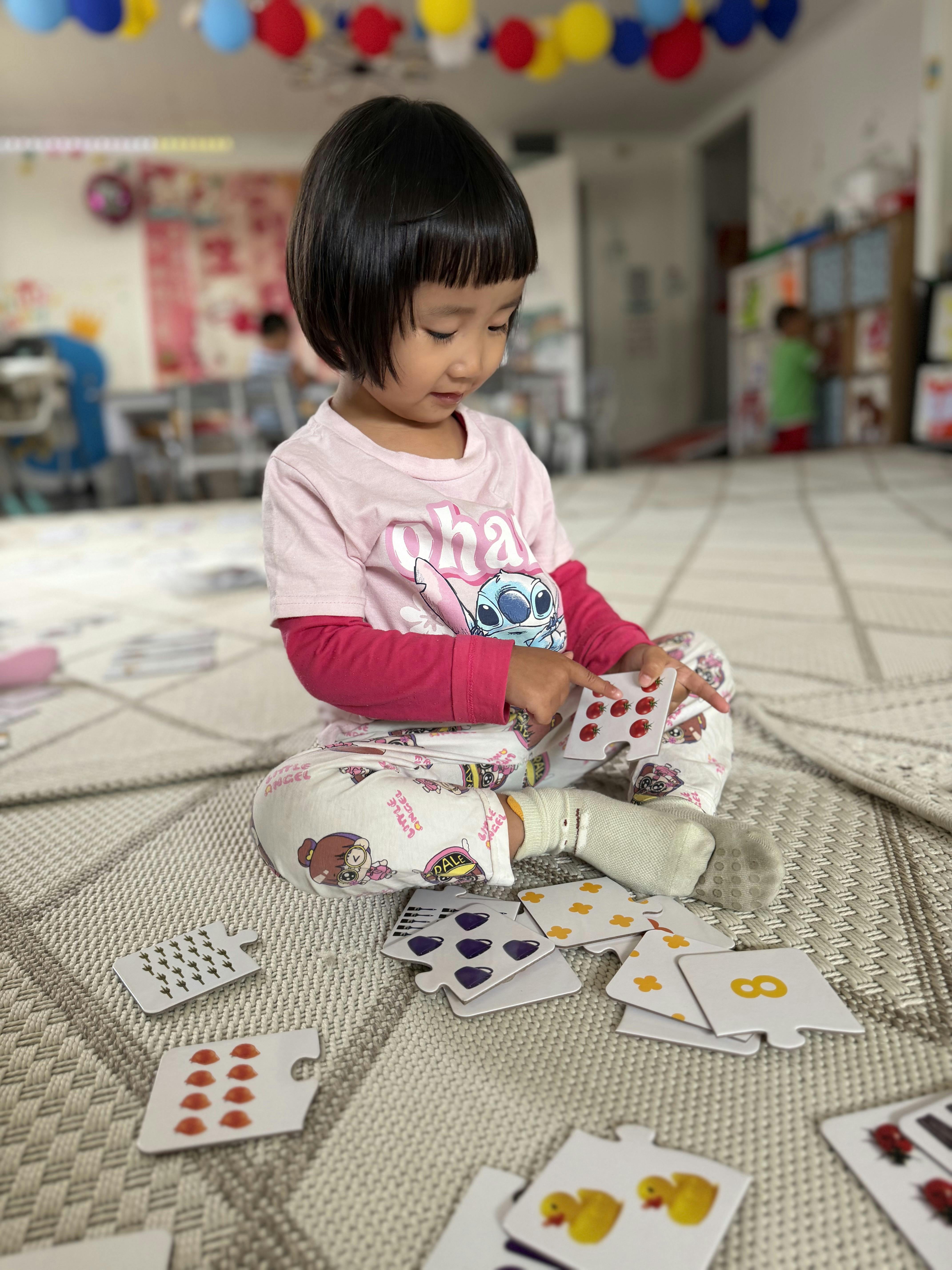 Child sitting on floor playing with educational counting puzzle cards