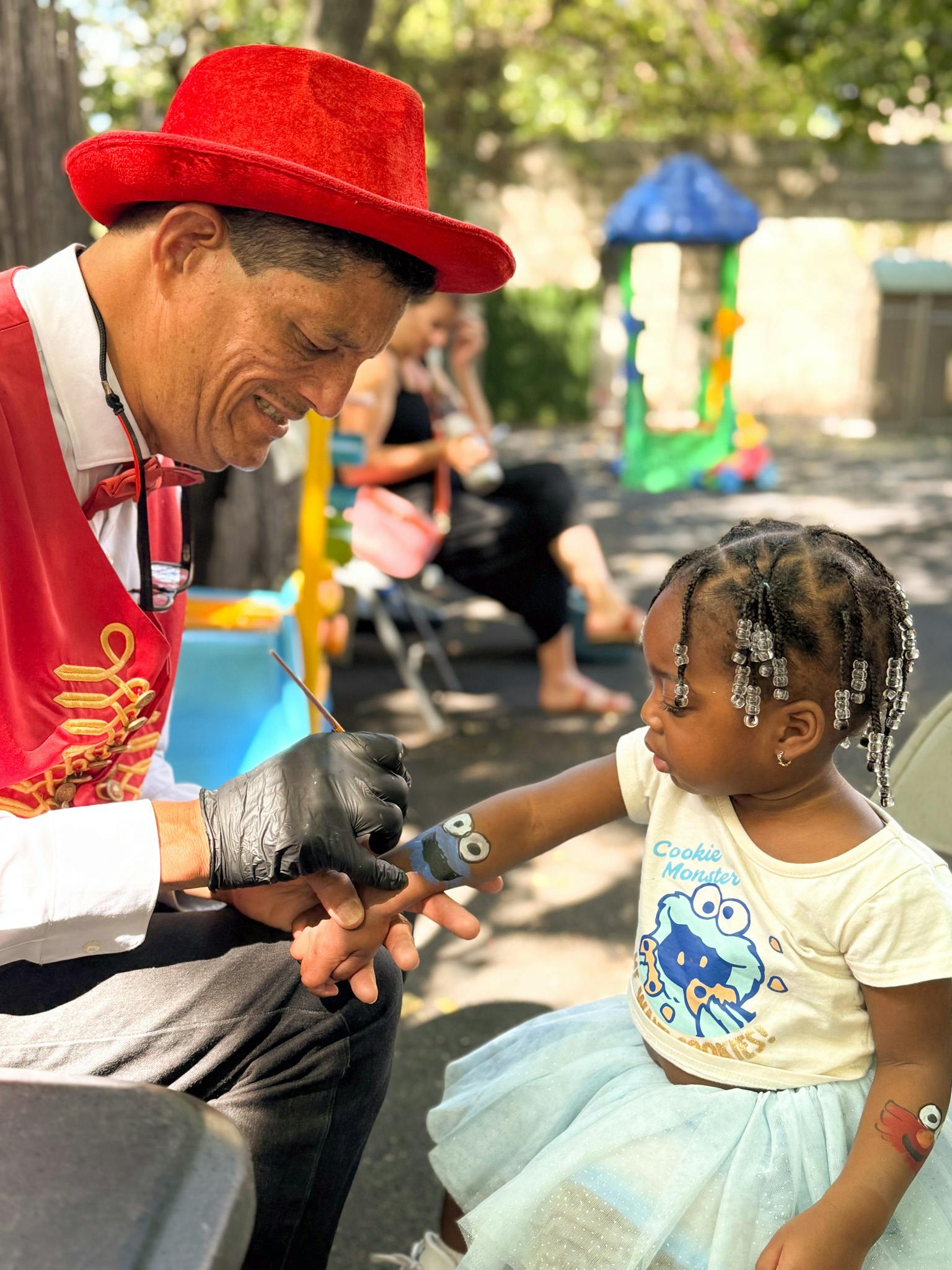 Performer in costume face painting a child on an outdoor playground