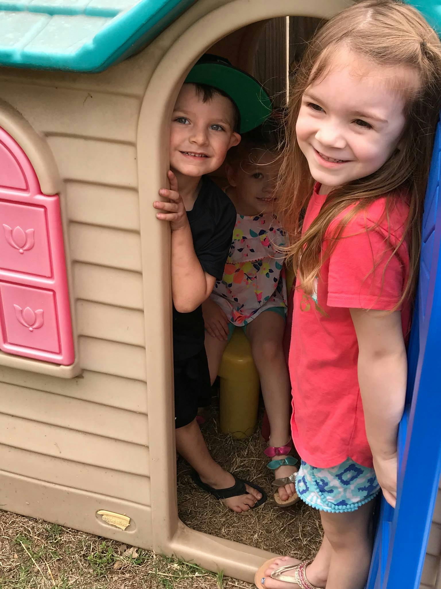 Three children peeking out of a playhouse