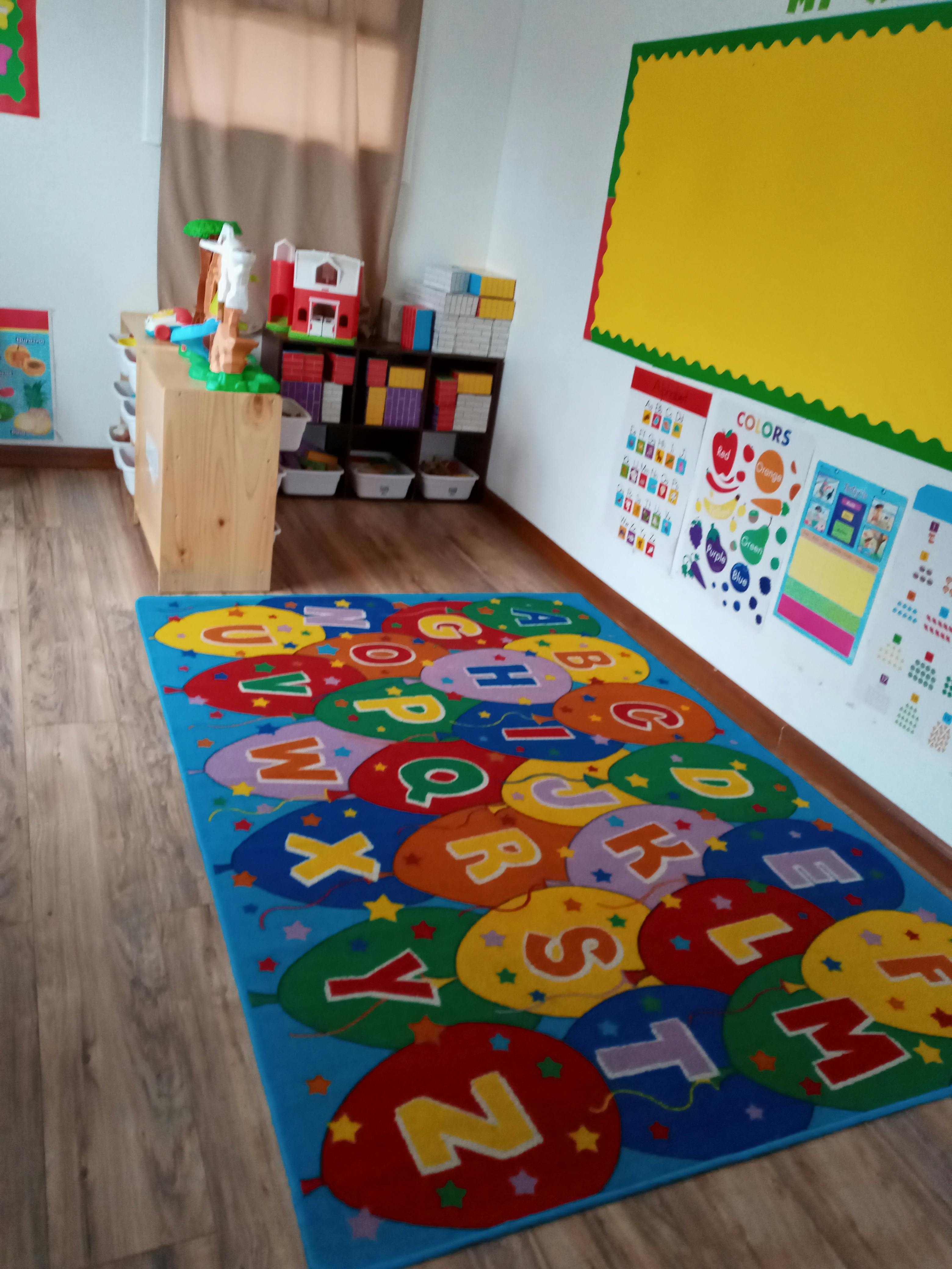 Classroom with an alphabet rug, toys, and educational posters