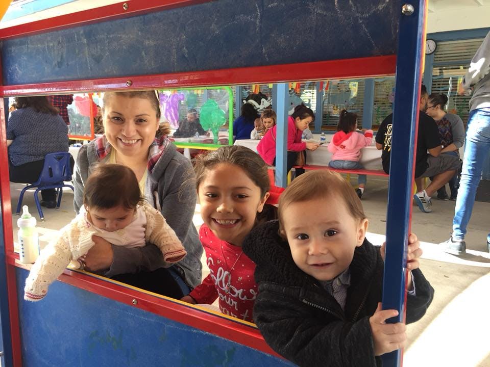 Person holding a child, another child, and a toddler looking through a frame
