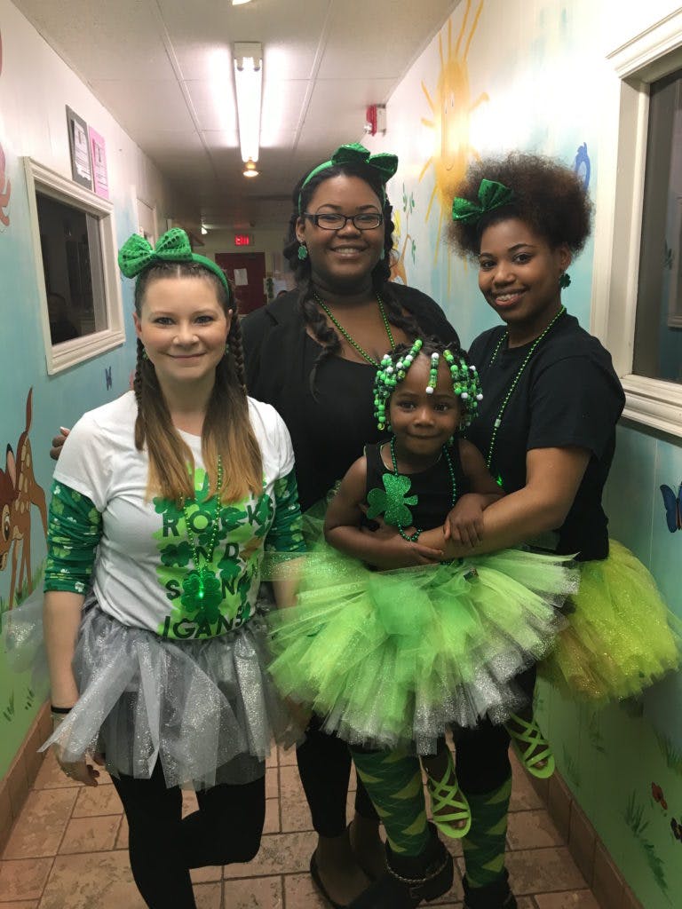 Three people and a child in green outfits with shamrock decorations