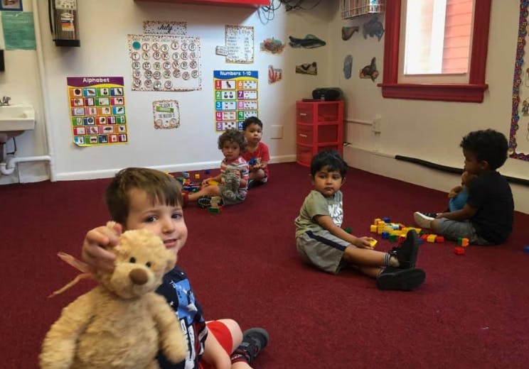 Children playing on a red carpet in a classroom