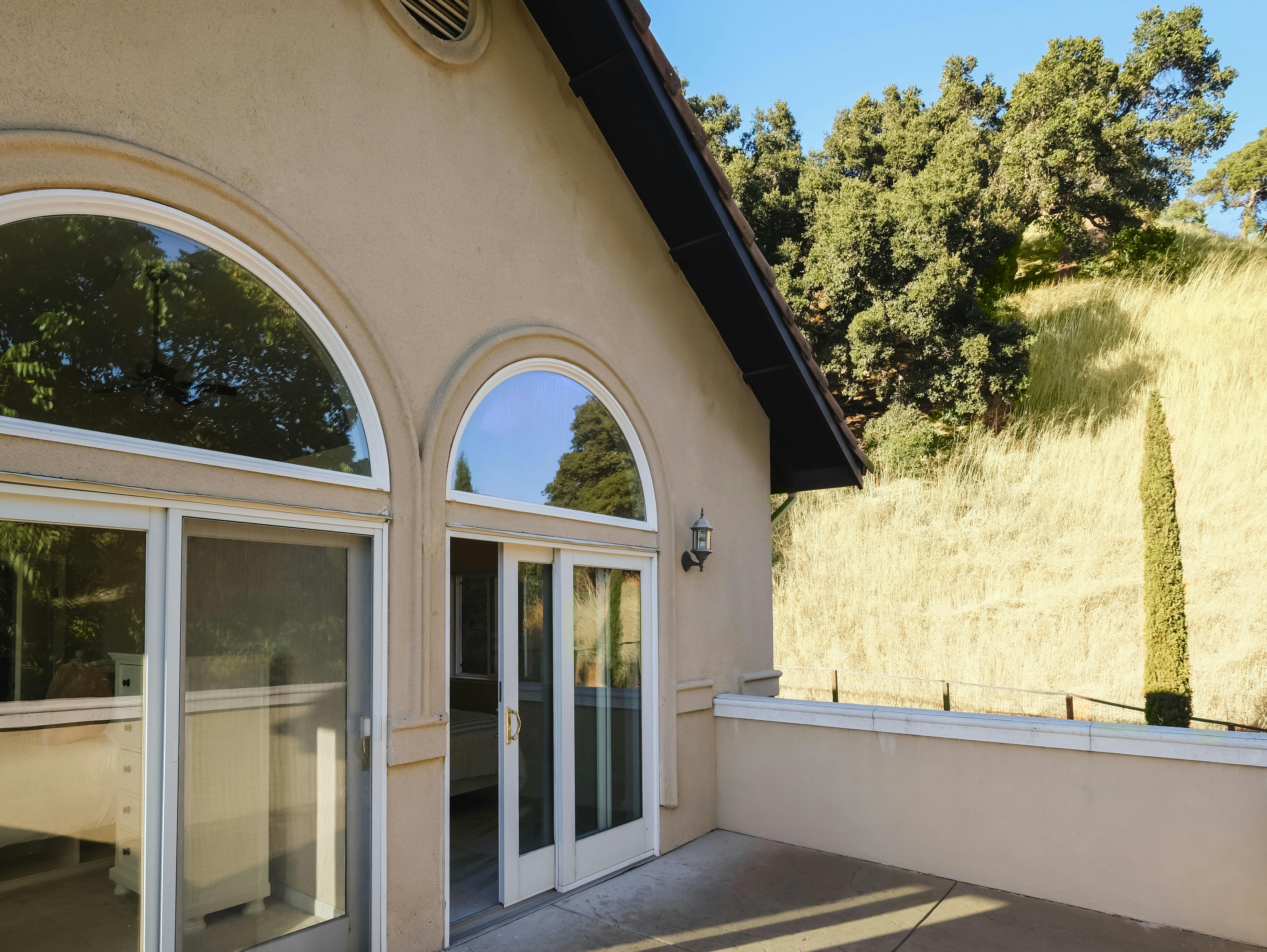 Exterior of a building with arched windows and doors, hillside in background