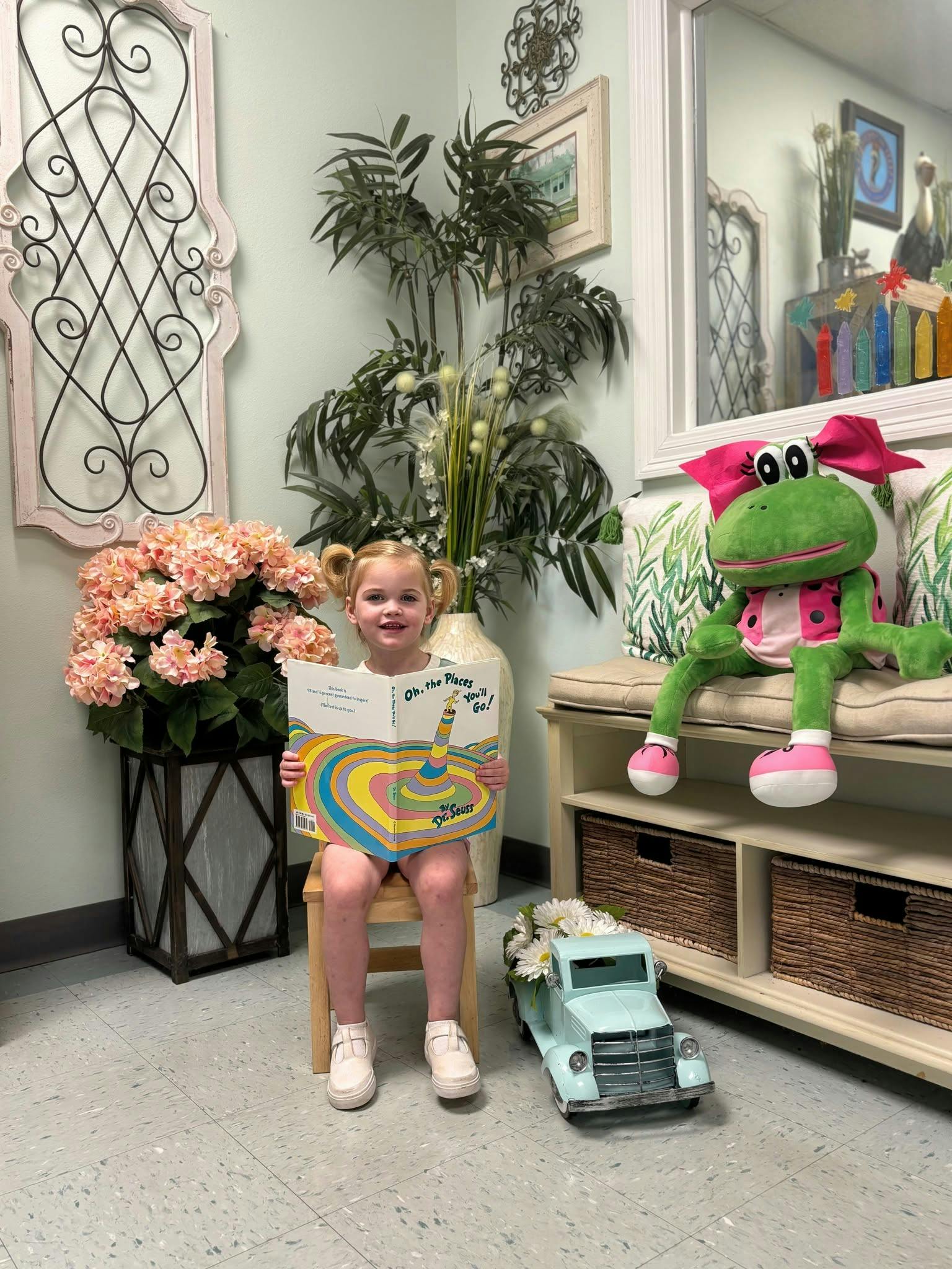 Child sitting on a chair holding an Oh, the Places You'll Go book