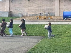 Children walking and running with balls outdoors
