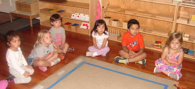 Five children sitting on the floor in a classroom