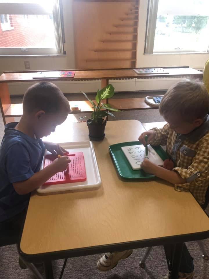 Two children working at a table with learning materials