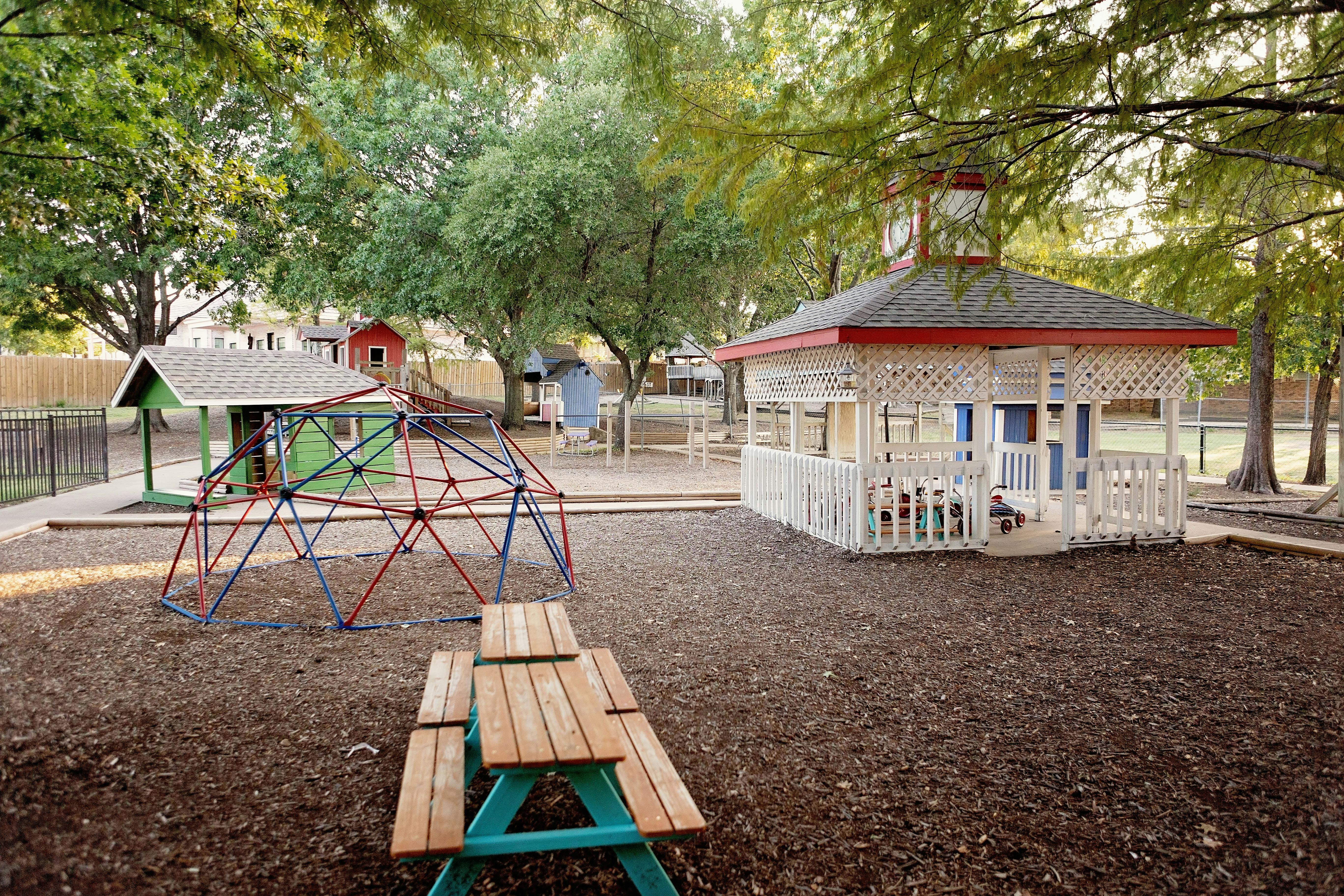 Playground with a geodesic dome climber, small house, and picnic table