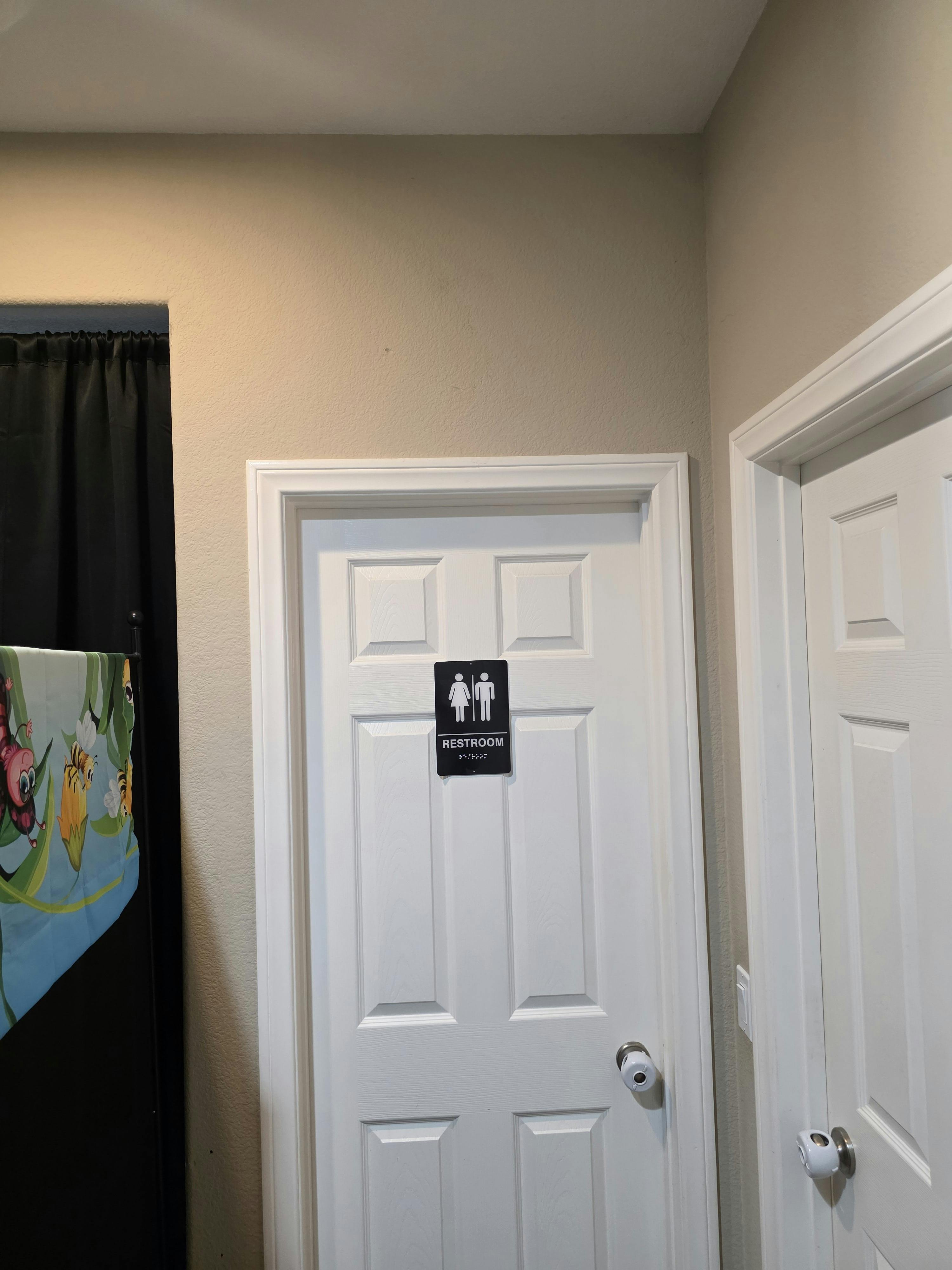 Black sign with male and female figures and the word "RESTROOM" on a white door