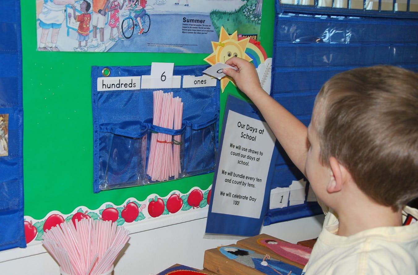 Child placing a number card on a classroom display