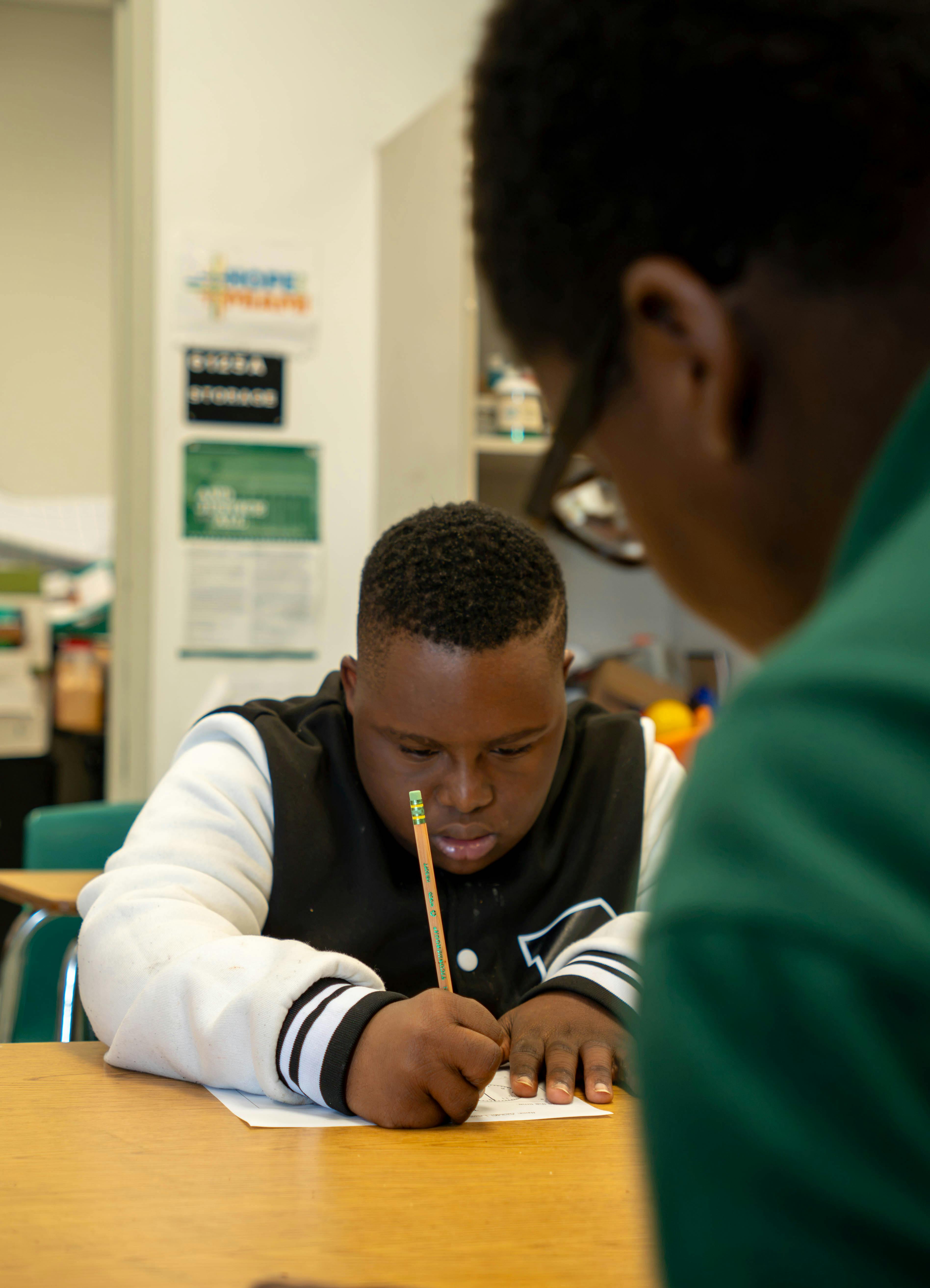 Child writing with a pencil at a desk