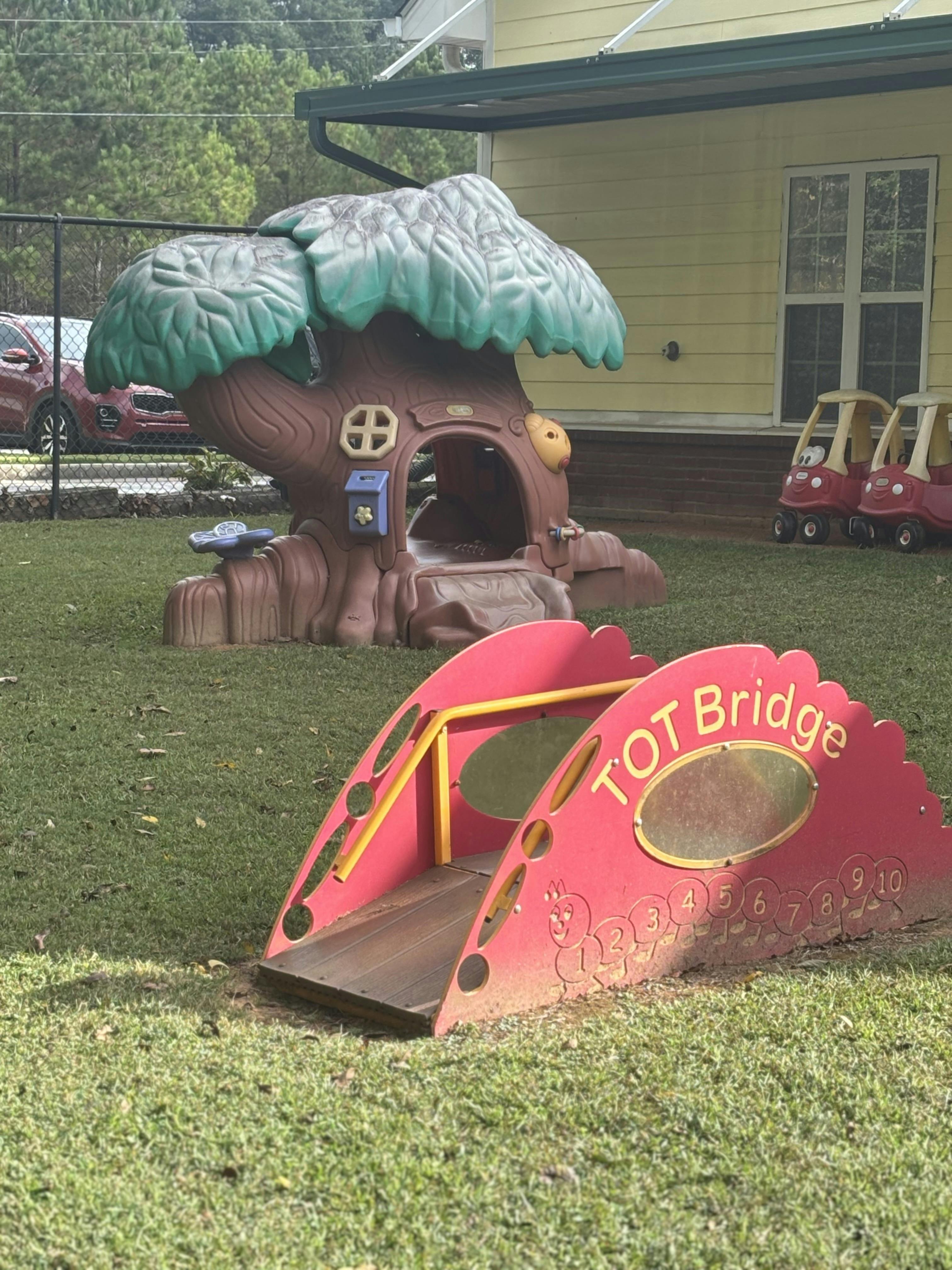 A children's playground with a red bridge with text "TOT Bridge" and a treehouse