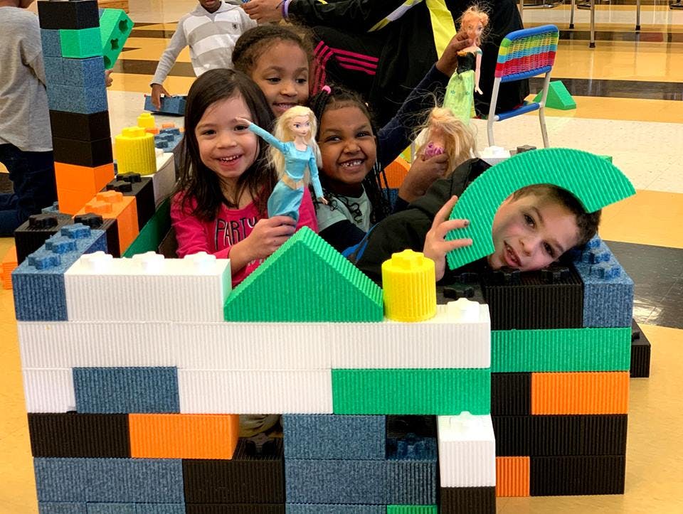 Children playing with large building blocks and dolls