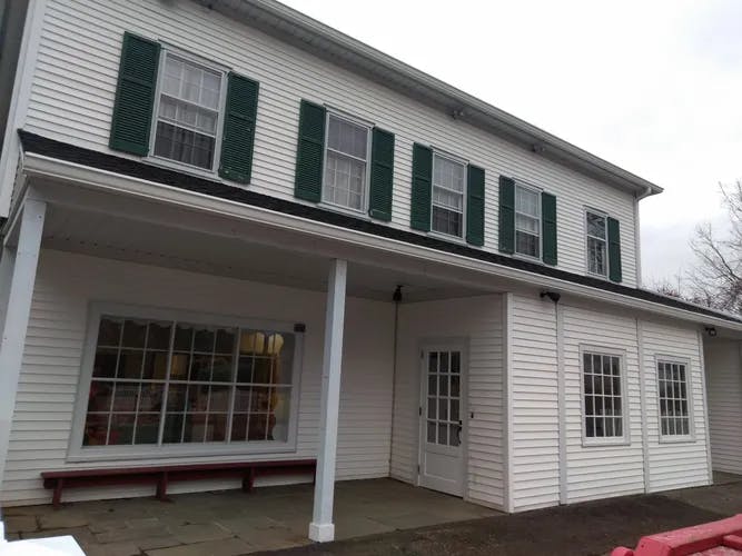 White house with green shutters and a covered porch