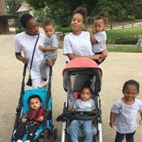 Two adults with four children, two in strollers and one standing