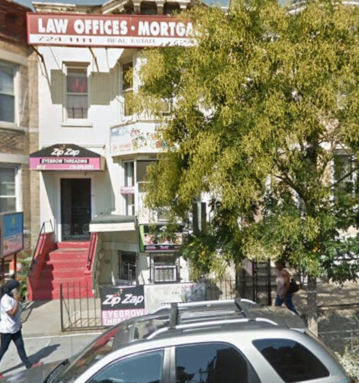 Building with "Law Offices Mortgage" sign and red stairs, person walking